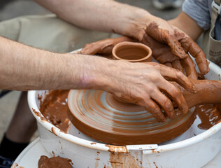 The potter teaches a young student.