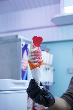 A Worker With Gloves Holding An Ice Cream Cone With A Mix Flavours Pink And Vanilla. Pink Ice Cream With A Red Heart On Top. Having It Inside An Ice Cream Truck.