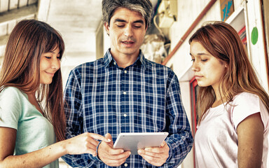 Teacher explaining to two girls using tablet
