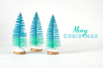Merry Christmas greeting with bottle brush ombre blue trees on white background for bright and cheerful holiday banner.