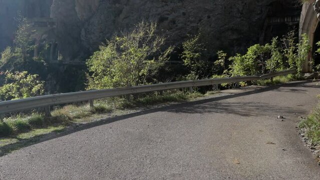 An old abandoned highway in the mountains. Rock and tree collapses, rockfalls on the road. Rocks, mountain gorge. Damaged bumpers on the side of the road.