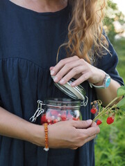 a woman holds a jar with strawberries in her hands