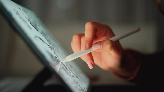 Woman painting on tablet pc in the night at home