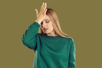 Forgetful young woman taps her forehead with her hand, remembering something too late. Beautiful...