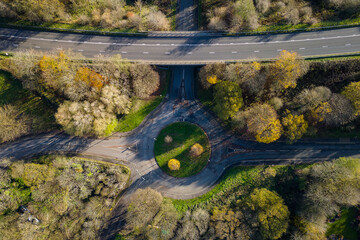 Aerial view of a small traffic roundabout on a rural road with fall (autumn) colored trees