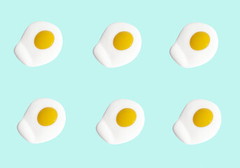 Fried eggs, scrambled eggs on blue background in food pattern. View from above. Food fashion minimalistic concept. 