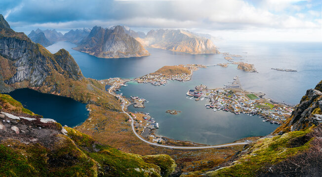 Panorama view during sunset or sunrise from the top of Reinebringen, Norway. View from mountain on fjords and Reine fishing village in Lofoten island. Steep mountains.