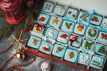 Delicious Christmas cookies set in a gift box. Advent calendar to count the days in anticipation of Christmas. Gingerbread cookies with festive blue icing on the Christmas background