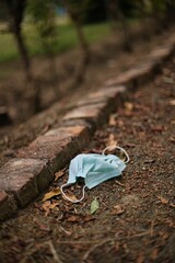 Old face mask on the ground with autumn leaves
