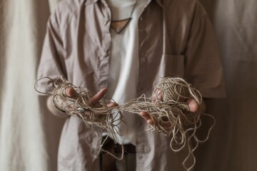 Vertical closeup of a man's hands holding a fibers silk cotton linen jute rope