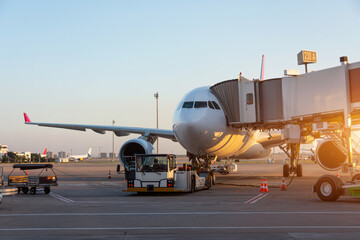 Aircraft is attached to the terminal gangway of the airport building preparation for towing and...