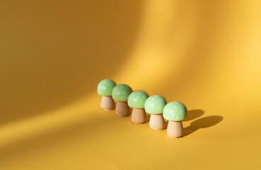 Wooden mushrooms in a row on a yellow background. Spaced copy.