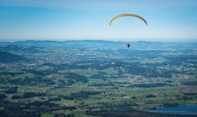 Aerial view of a person paragliding with the city and a blue sky in the background