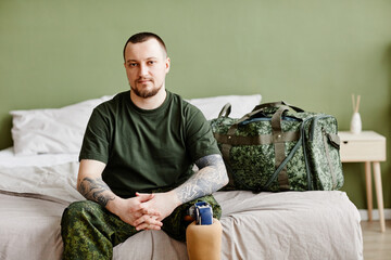 Portrait of military veteran with prosthetic leg looking at camera at home and wearing army uniform, copy space - obrazy, fototapety, plakaty