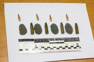 Bullet, cartridge case, cartridge, forensic ruler on a sheet of white paper