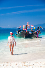 woman on beautiful tropical beach in Thailand with longtail boats