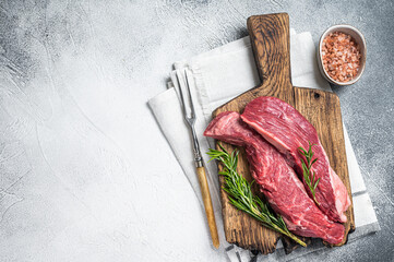 Butcher choise Bavette raw beef meat steak or flank flap on a wooden board with herbs. White...