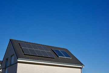 Fototapeta premium House with solar panels covering its tiled roof under a clear blue sky on a sunny day