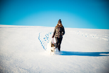 woman and her happy white dog enjoying winter snow outdoors on sunny day