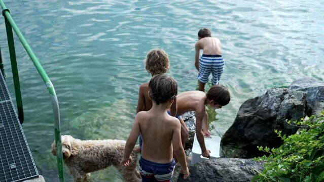 Small boys by lake water during vacations. Children enjoying nature outdoors wearing bathing suits. Kid having fun fishing