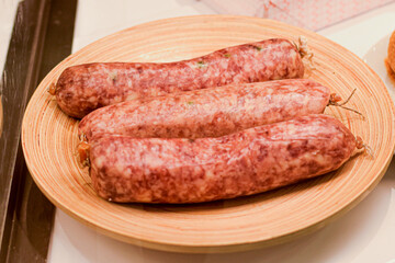 traditional meat sausages being served raw on the wooden plate