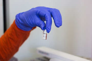 A hand in a rubber glove holding a vial close-up