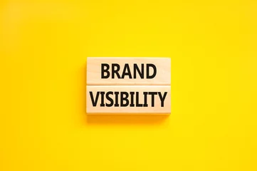 Fotobehang Brand visibility symbol. Concept words Brand visibility on wooden blocks. Beautiful yellow table yellow background. Business branding and brand visibility concept. Copy space. © Dzmitry