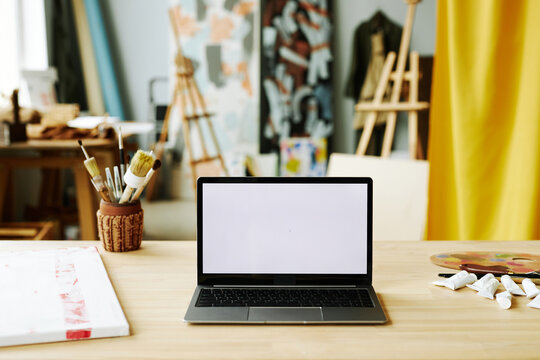 Workplace of creative designer or digital artist with wireless computer with blank screen in studio of contemporary arts