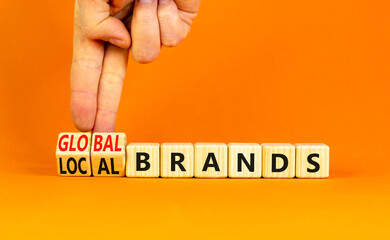 Global or local brands symbol. Concept words Global brands and Local brands on wooden cubes. Businessman hand. Beautiful orange background. Business global or local brand concept. Copy space.