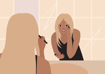 Woman applying makeup in the bathroom. Beautiful tanned blonde girl is reflected in the mirror and applies make up. Young woman standing in front of a mirror. Girl draws arrows on her eyes