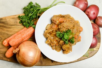 Beef stew with ingredients on wooden board