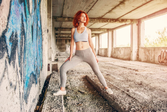 Fitness woman in sportswear doing stretching exercise on city street over gray concrete background. Outdoor sports clothing and shoes, urban style.
