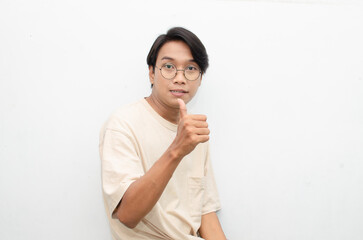 handsome attractive Asian man smiling happily and giving thumbs up as compliment isolated over...