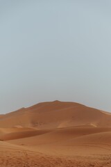 Fototapeta na wymiar Orange sand Dunes in the desert with the light blue sky background