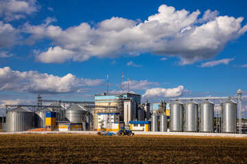 Agricultural Silos. Storage and drying of grains, wheat, corn, soy, sunflower against the blue sky with white clouds.Storage of the crop © Sergii