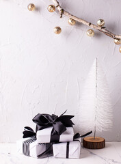 Modern white decorative Christmas tree and  group of wrapped boxes with presents on white textured backgrond. Place for text.