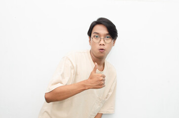 handsome attractive Asian man smiling happily and giving thumbs up as compliment isolated over white background. man giving approval and compliment by gesturing thumbs up.