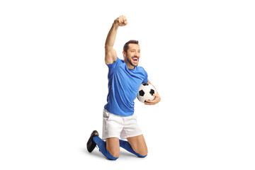 Excited fotball player holding a ball and kneeling