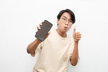 excited young asian man in beige tshirt holding and showing phone screen with happy euphoric...