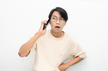 excited young asian man in beige tshirt holding and showing phone screen with happy euphoric shocked wow expression. man pointing to screen phone with thumb up. billboard model advertisment concept.