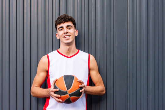 Male basketball player with ball against dark background