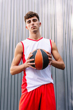 Male basketball player with ball against dark background