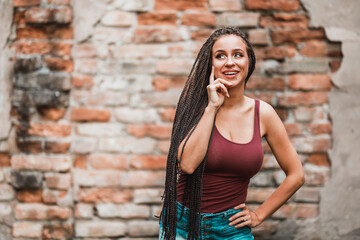 Woman With Long Afro Braided Hair Standing Against A Brick Wall