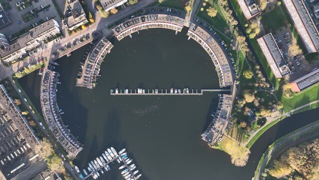 Harbour of Weesp, Aquamarin around the former industrial harbor. Suburban residential real estate housing in the shape of a circle. Small port recreactional living along the water. Aerial.