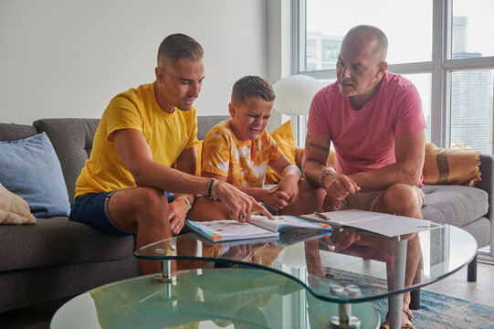 Same sex male couple helping son with homework.