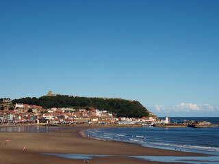 Fototapeta na wymiar view of scarborough south bay with beach and town on a sunlit summer day with the harbour and castle in the distance