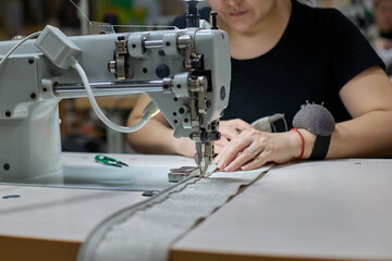 Seamstress or an employee of an Asian textile factory sewing on an industrial sewing machine....