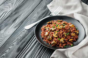 delicious red rice with mushrooms on a black wooden rustic background