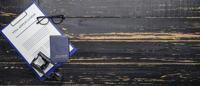 Visa application form, passport and stamp on dark wooden background with space for text. Concept of immigration
