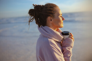 relaxed stylish female in cosy sweater at beach in evening